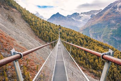 Footbridge over mountain against sky