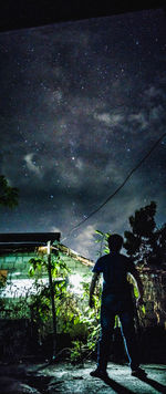 Rear view of man standing against sky at night