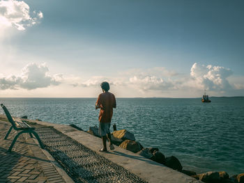 Rear view of men by sea against sky