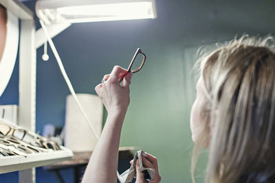 Female owner examining eyeglasses frame in workshop