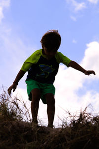 Full length of boy standing on field against sky