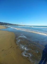 Scenic view of beach against clear blue sky