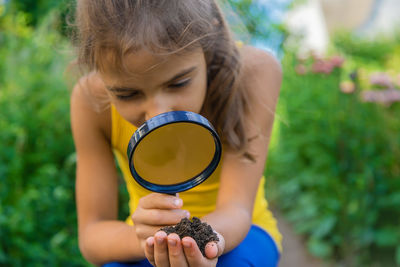 Close-up of woman holding sunglasses against plants