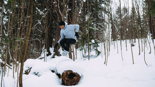 Young man jumping on snow covered field