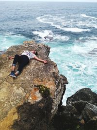 High angle view of woman on rock at sea shore