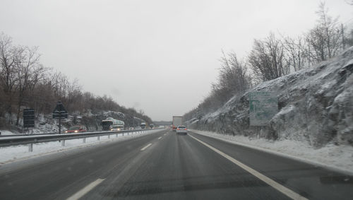 Cars on road against sky during winter