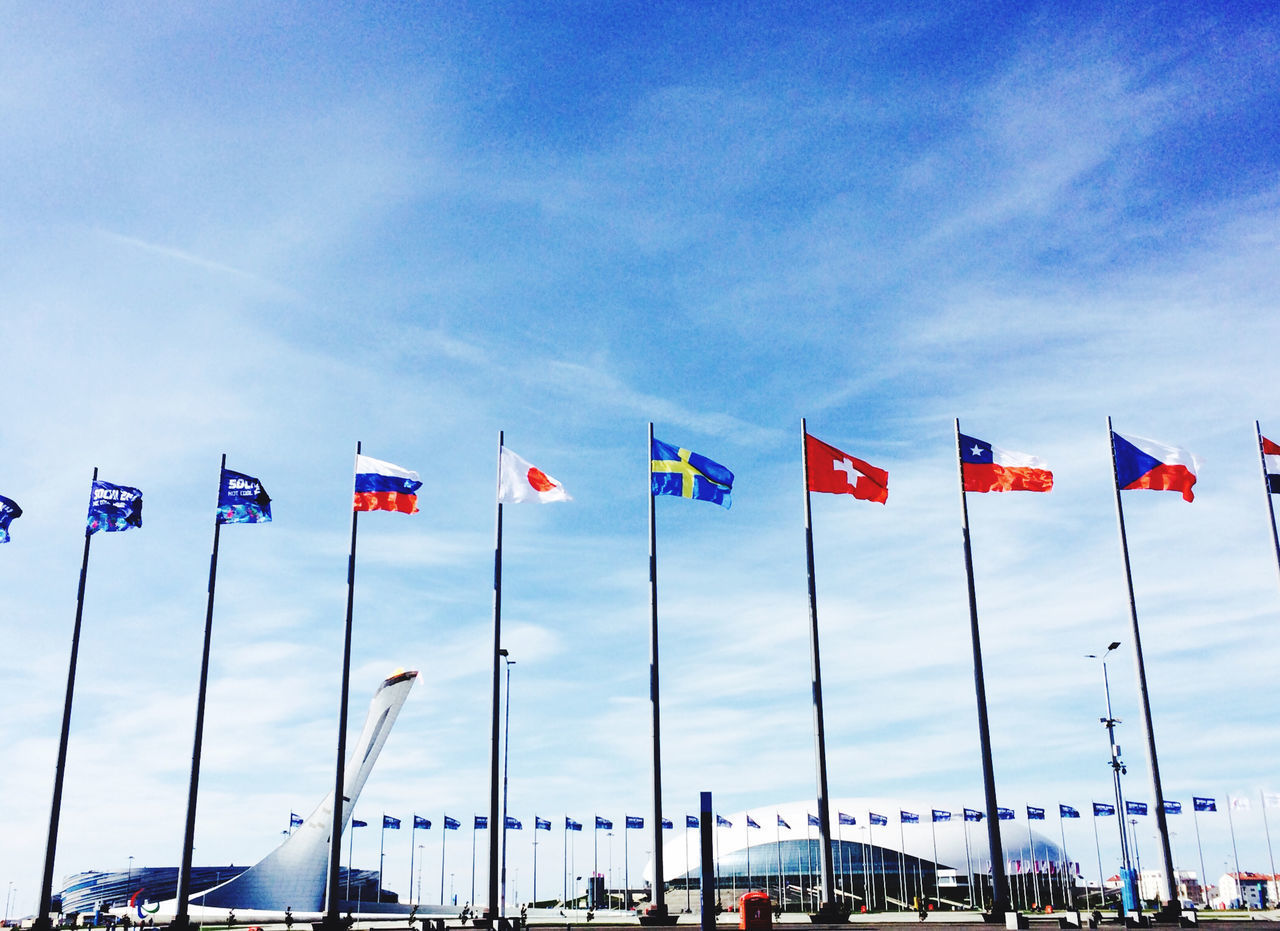 LOW ANGLE VIEW OF FLAGS AGAINST BLUE SKY IN CITY