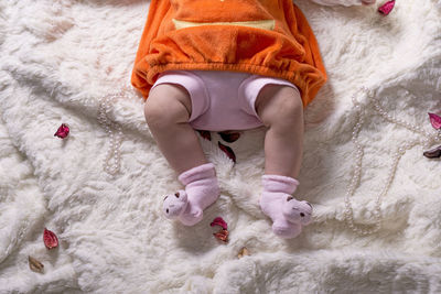 Low section of child lying on bed