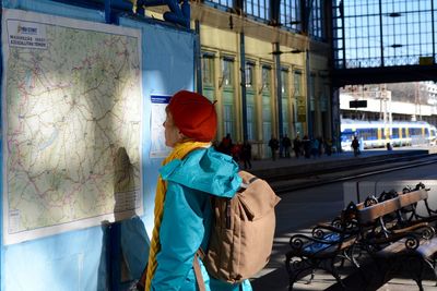 Side view of woman reading map at railroad station