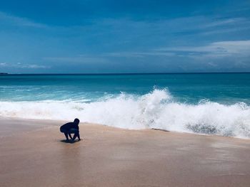 Rear view of man on beach against sky