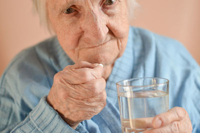  an elderly 90-year-old gray-haired woman who holds a tablet and a glass of water in his hands. 