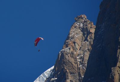 Low angle view of person paragliding against clear blue sky