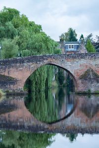 Arch bridge over lake against sky