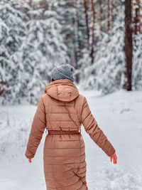 Rear view of woman standing on snow covered field