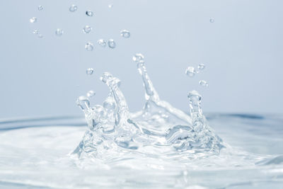 Close-up of drop falling in water against white background
