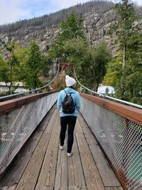 Rear view of woman walking on footbridge