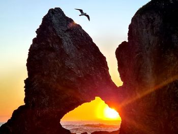 Low angle view of rock formation on sea against sky during sunset