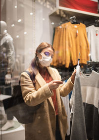 Woman wearing mask while looking at garments