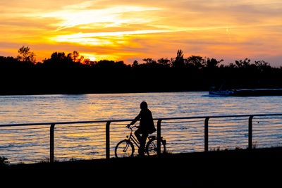 Silhouette of people on lake at sunset