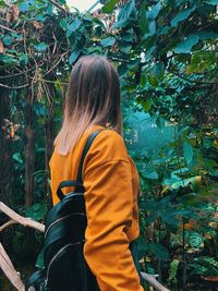 Side view of woman with backpack standing in forest