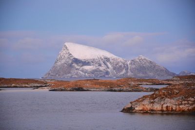 Scenic view of sea by snowcapped mountain against sky