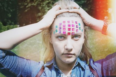 Close-up portrait of mid adult woman with colorful stickers on forehead