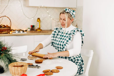 A young woman in an apron makes curly cookies for christmas. the concept of christmas and new year.