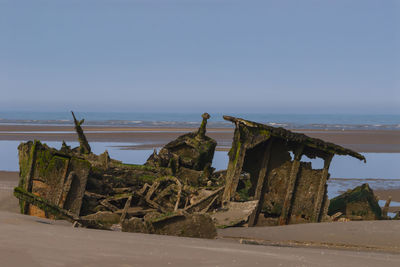 Abandoned built structure on beach against clear sky