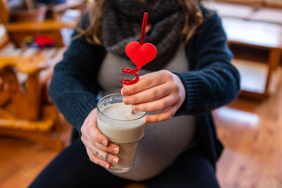 Midsection of woman drinking milk shake at cafe