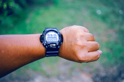 Close-up of human hand wearing wristwatch outdoors