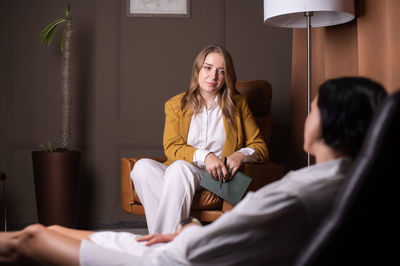 A young female psychologist listens attentively to a client sitting on a couch