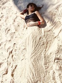 High angle view of woman buried in sand at beach