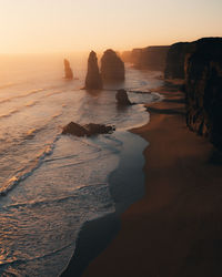 Rocks on beach against sky during sunset