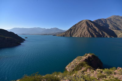 Scenic view of lake potrerillos, and mountains of los andes against clear blue sky