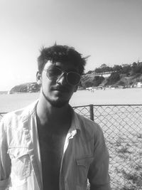 Portrait of young man wearing sunglasses standing against clear sky