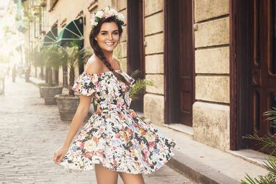 Portrait of smiling woman standing at footpath