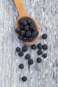 High angle view of blackberries with wooden spoon on table