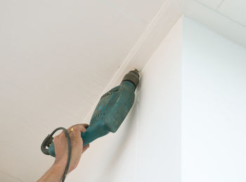 Close-up of hand holding umbrella against white wall at home