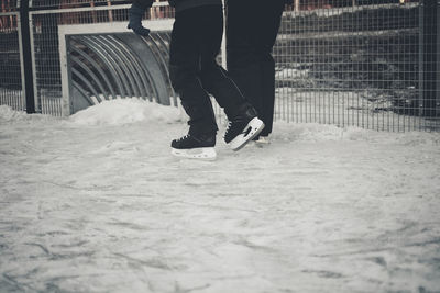 Low section of men ice-skating on snowcapped field