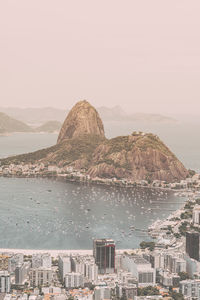 Aerial view of city by sea against sky