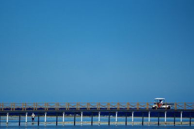 Bridge over sea against clear blue sky