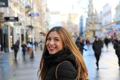 Portrait of smiling woman standing in city during winter