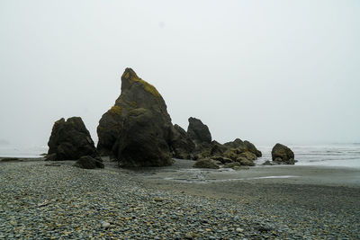 Rock formation on beach against clear sky