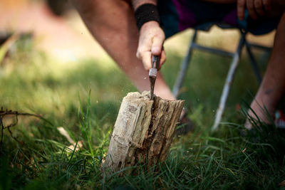 Midsection of person cutting wood on field