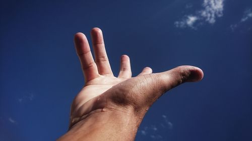 Cropped hand gesturing against sky