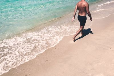 Full length of shirtless man at beach