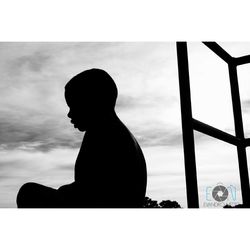 Side view of silhouette woman sitting against sky