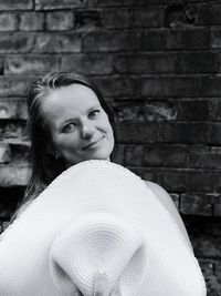 Portrait of smiling mid adult woman holding hat against wall