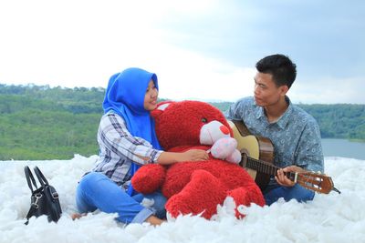 Men sitting on playing against sky