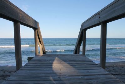 Boardwalk at beach against sky